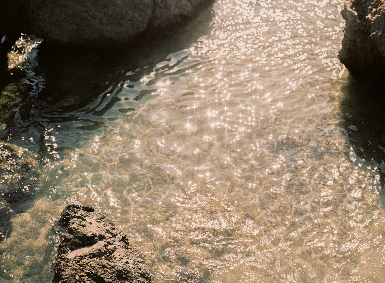 Clear, sunlit water running over smooth stones