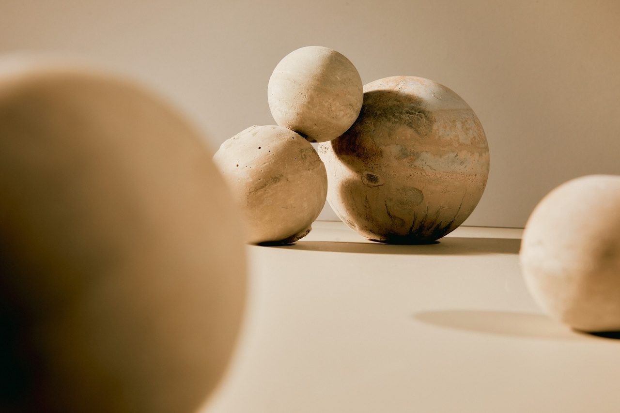 Weathered stone spheres resting on a warm tabletop, one large sphere in focus among smaller ones